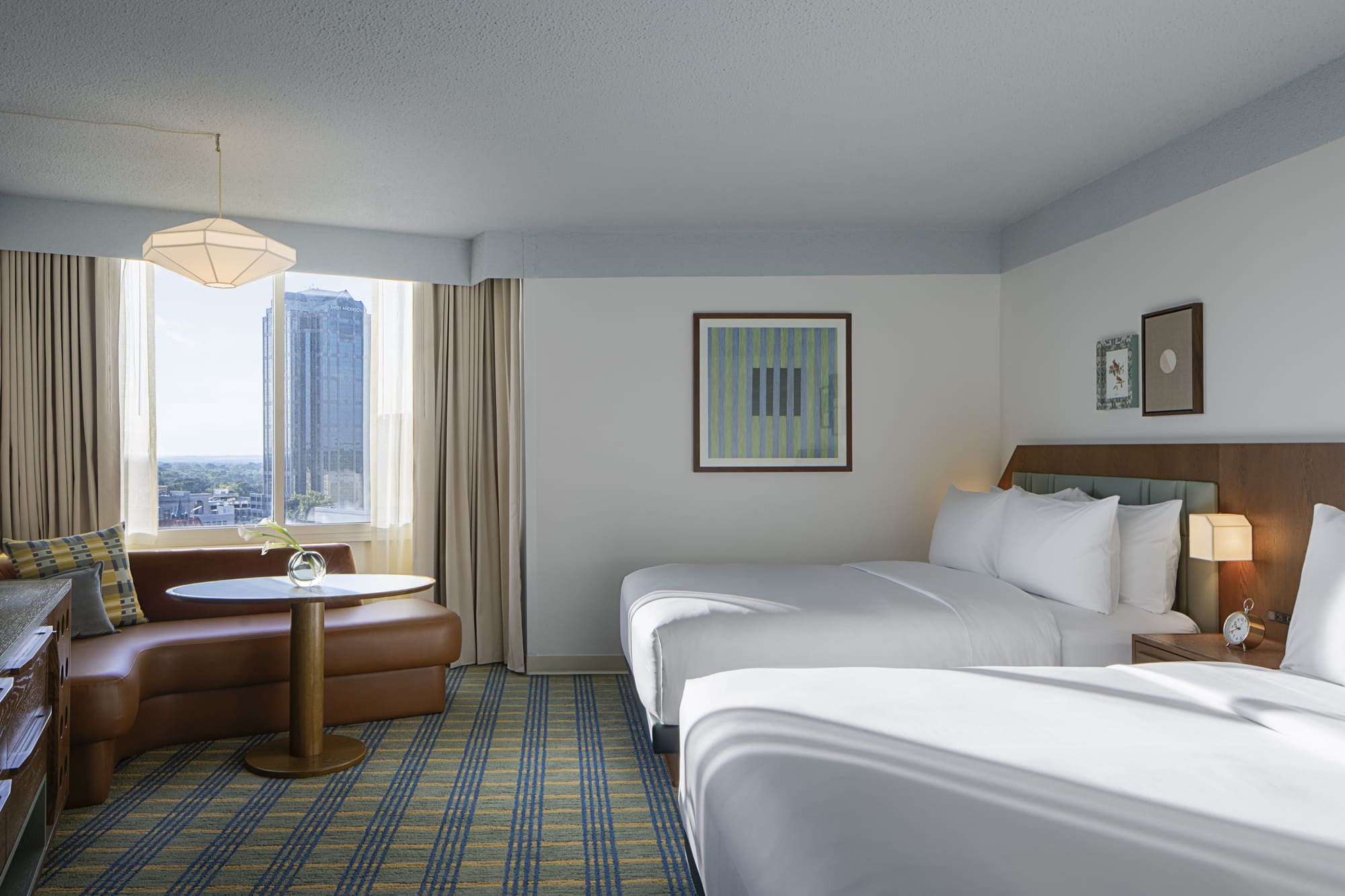 A hotel room with a double bed, a window with a view, and a small table by the bed.