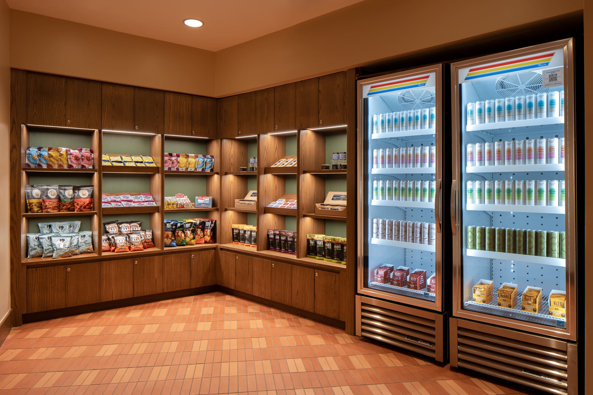 A grocery store corner with a glass-fronted refrigerator and wooden shelving, featuring various food items.