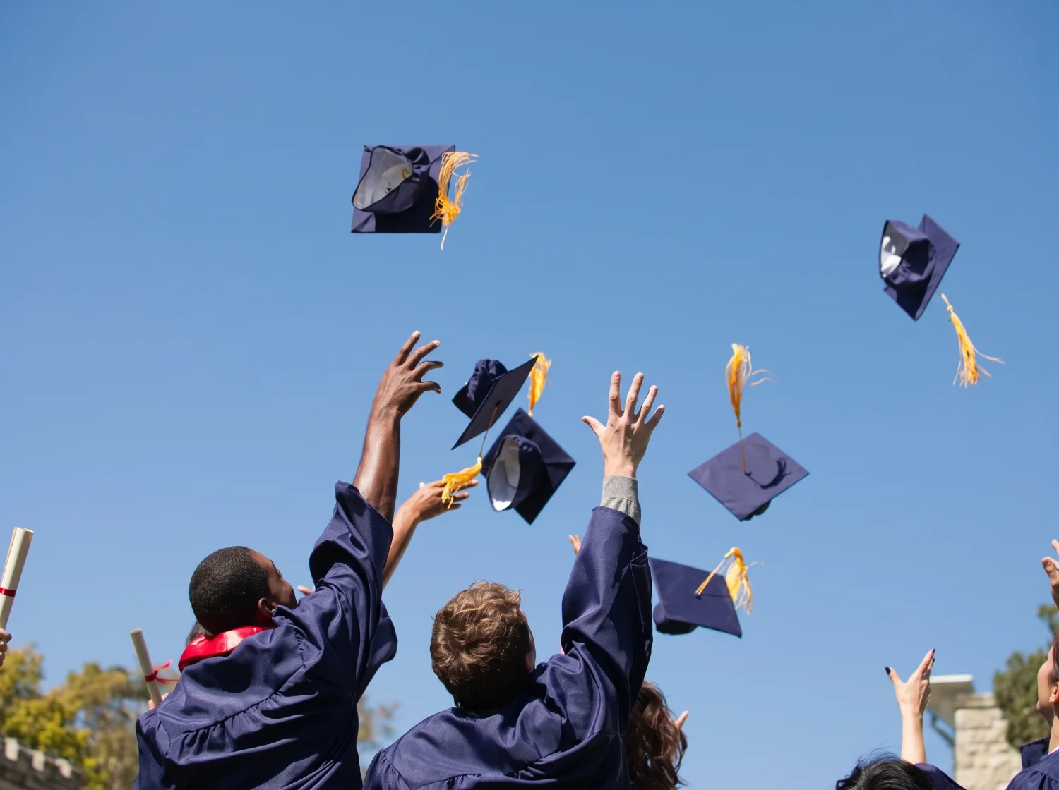 Graduates tossing their caps into a blue sky at commencement